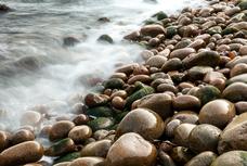 Wet pebbles on beach with blurred water, Maine, USA